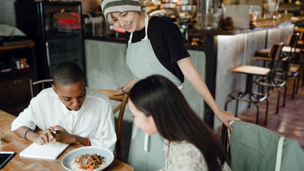 Cheerful young waitress communicating with clients
