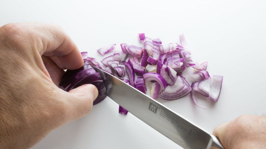 The person is chopping an onion.